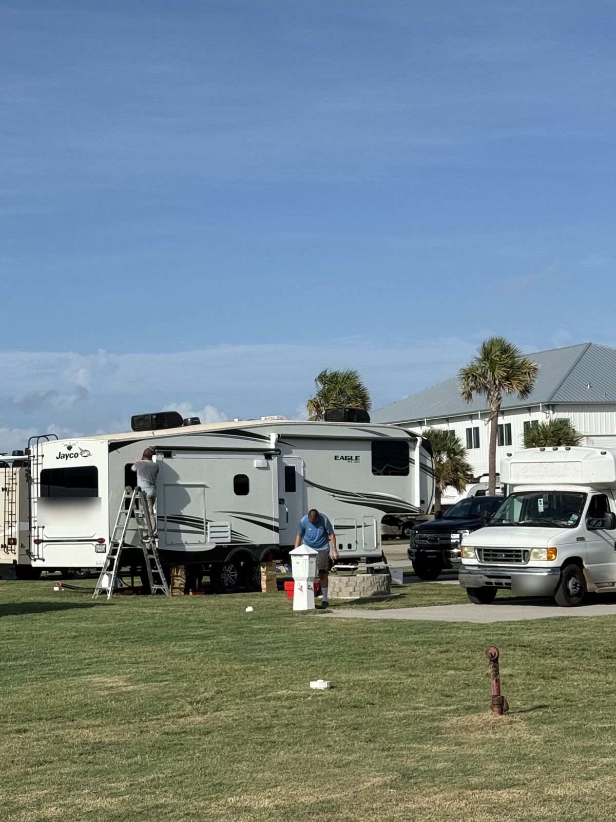 Two technicians servicing a fifth-wheel at its campsite
