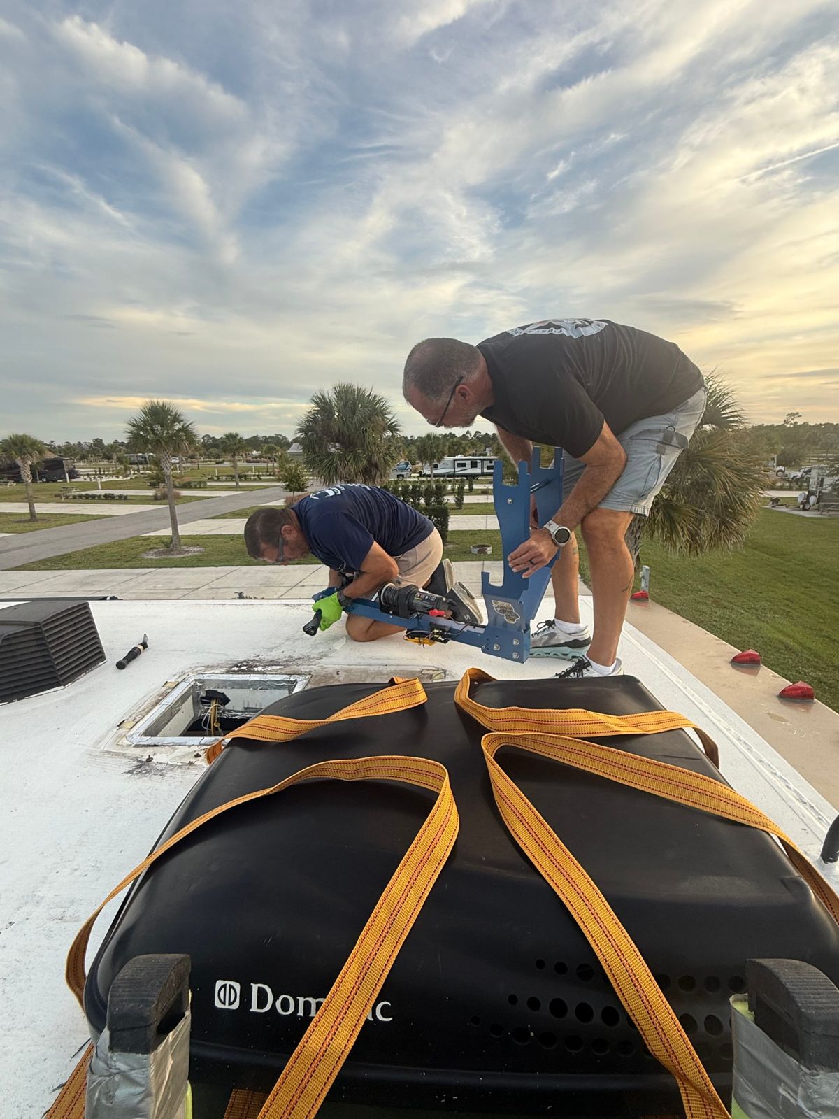 Two technicians setting up a roof hoist with the resort in the background