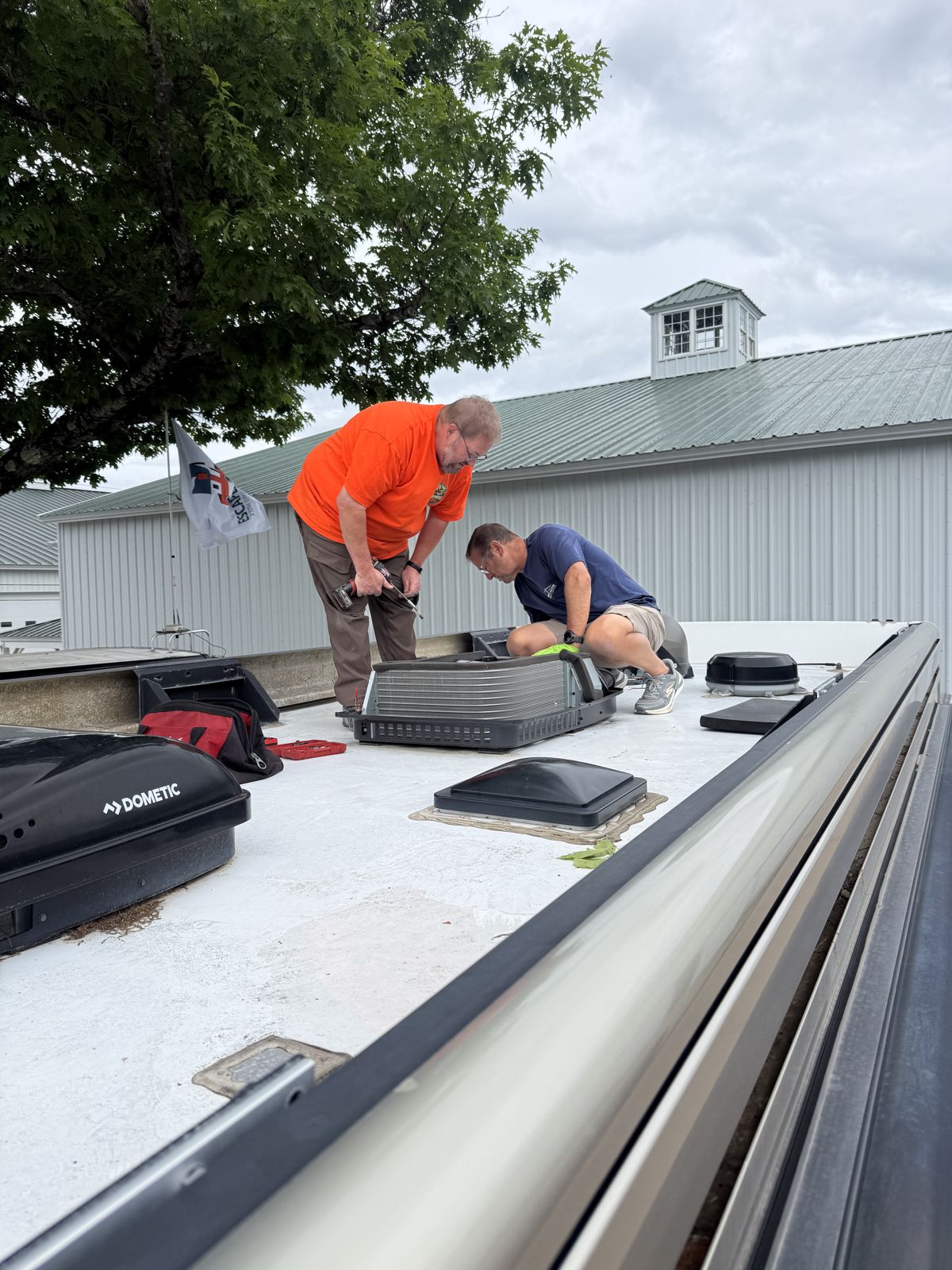 Two technicians servicing a rooftop air conditioner together