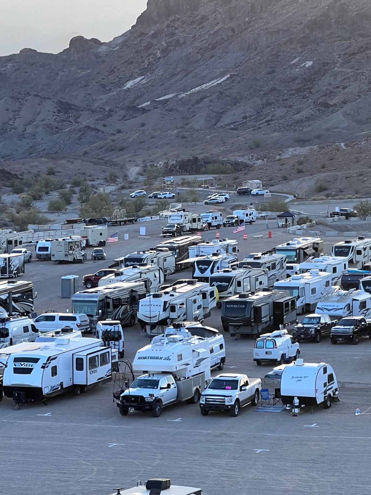 Rows of RVs parked at a desert rally beneath the mountains
